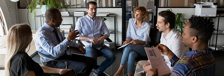 Six professionals engaged in a discussion, seated in a circular arrangement.